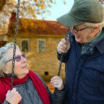 man standing beside woman on swing